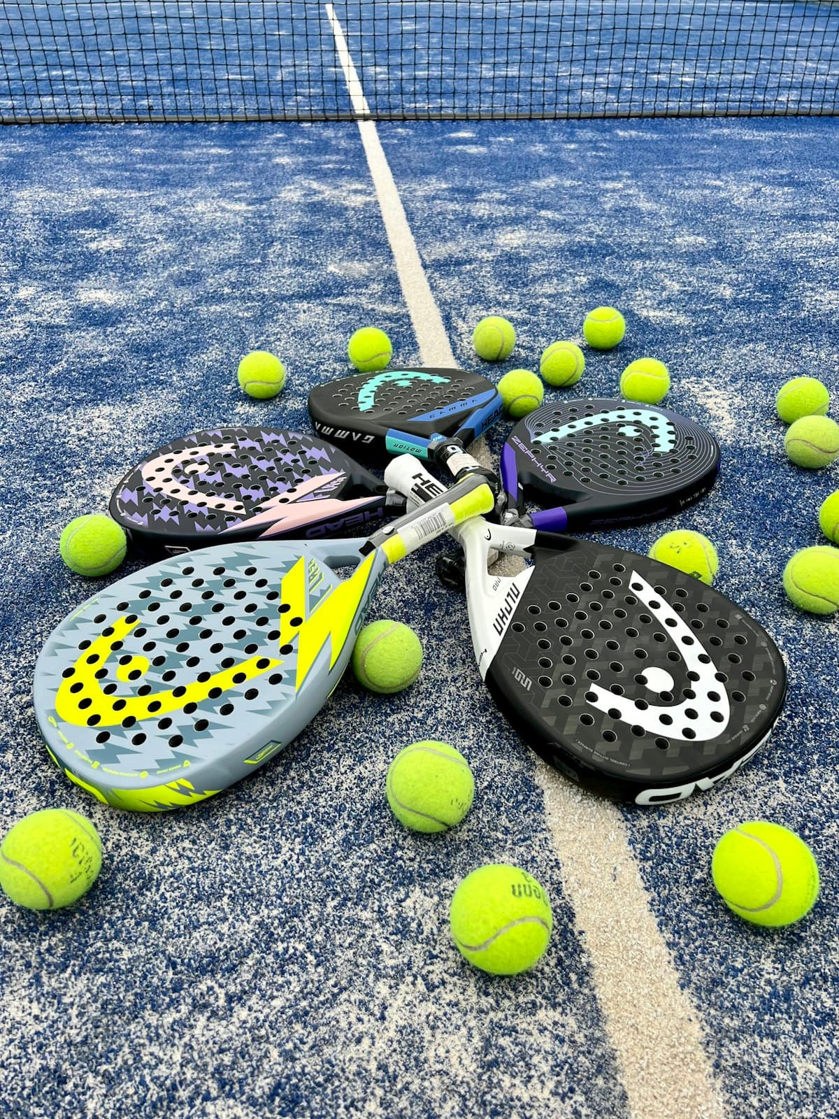 Palas de pádel y pelotas sobre una cancha azul